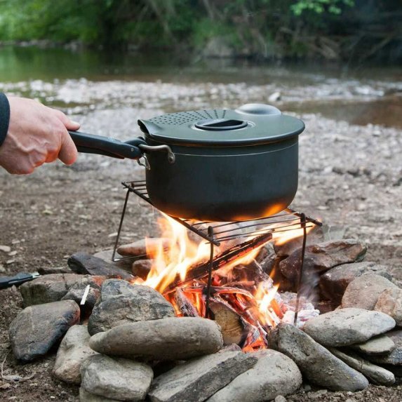 Kattila kannella, joka on asetettu telineelle avotulen p��lle, jossa ruoka valmistetaan luonnossa kivien ymp�r�im�ss� nuotiolla.